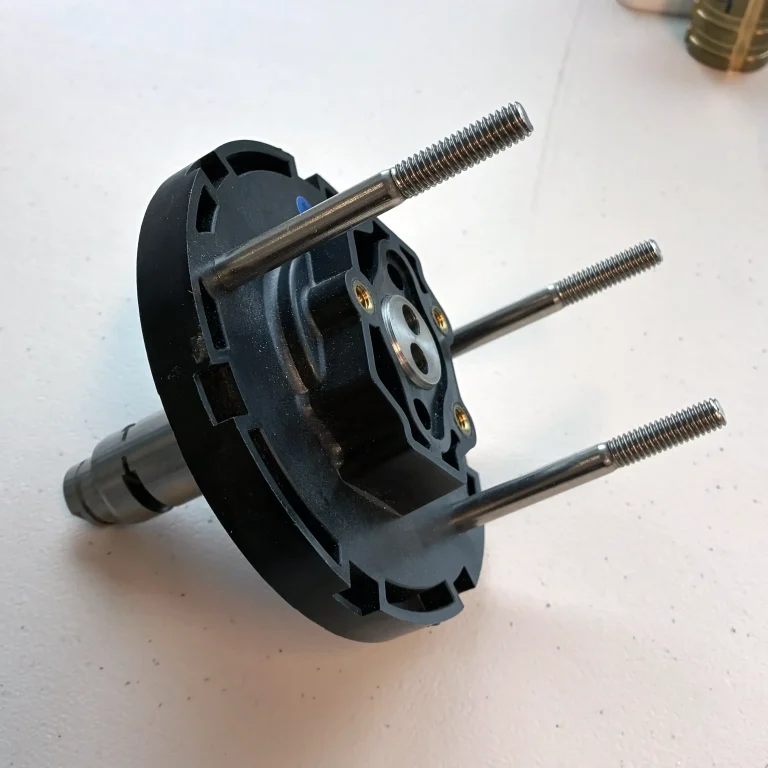 Engine part overmolded with bolts and shaft.